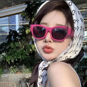 Detail of pink square sunglasses featuring a retro design and dark lenses on a model