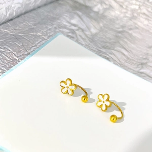 Detailed shot of golden flower stud earrings with white enamel petals and U-shaped pins