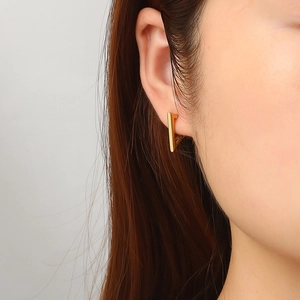 Boucle d'oreille triangulaire dorée en acier inoxydable portée par un modèle