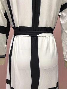 Detail of black and white geometric pattern dress with waist tie and long sleeves