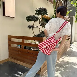 Detail of red and white striped canvas crossbody bag with wide matching shoulder strap