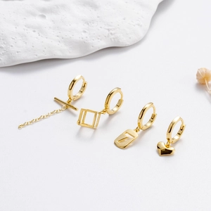 Minimalist gold earring set with chain, geometric, T-shape and heart styles on white background