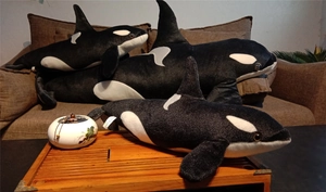 Three-piece set of plush orca dolls in different sizes on a sofa, close-up details