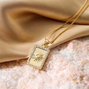 Macro shot of gold sunburst pendant with zircon border on elegant silk and stone