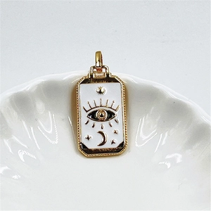 Detail of gold rectangular tarot pendant with eye and moon motifs on white shell plate