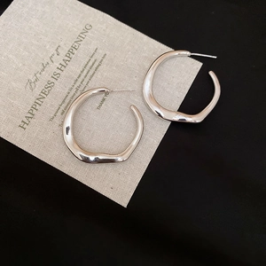 Detailed view of silver cross hoop earrings with greeting card on a dark background