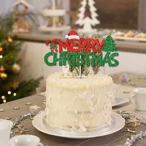 Glittery Merry Christmas cake topper with red hat and green tree on white festive cake