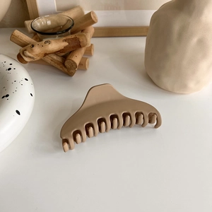 Detailed view of matte mocha hair claw clip with cross-tooth structure on wooden surface