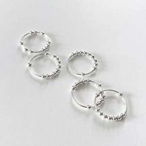 Detailed view of five 925 sterling silver minimalist beaded rings on a textured background