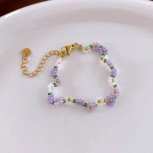 Detail of beaded flower bracelet with purple petals and heart-shaped charm clasp