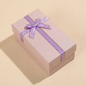 Macro detail of purple rectangular gift box with fine grid texture and golden bow