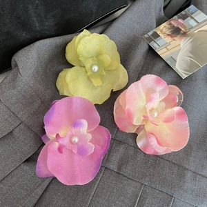 Elegant silk orchid hair claws with pearls in green, yellow, and purple floral designs