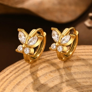 Macro shot of gold butterfly hoop earrings with sparkling cubic zirconia on wood