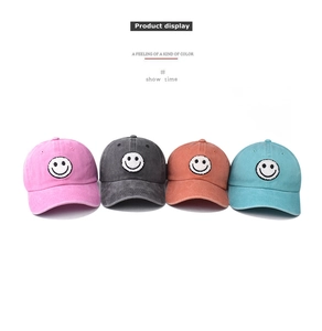 Detailed row of washed cotton baseball caps in pink, grey, orange, and blue with smile patch
