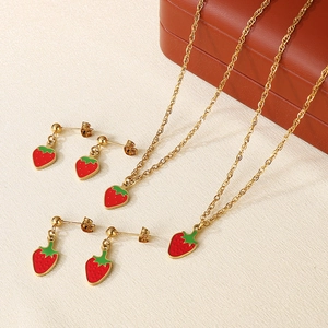 Detailed view of red enamel strawberry pendants on gold necklaces and stud earrings