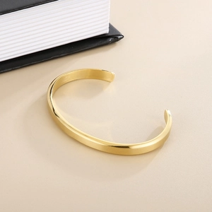 Primer plano de un brazalete en C minimalista de 6mm de acero inoxidable dorado con acabado cepillado