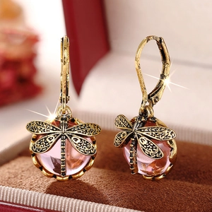 Makro-Detail von Vintage-Libellenohrringen in Altgold mit rosa Perlen im Etui