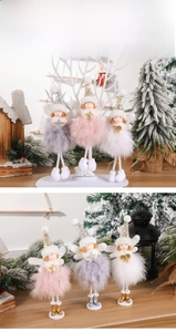 Three plush angel figurines with feather wings and sequined hats on winter branches