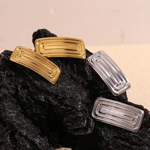 Detailed view of gold and silver textured arch hair clips on a black rock surface