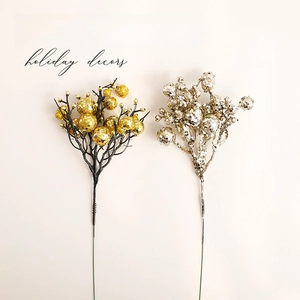 Golden and silver glitter Christmas berry picks decoration on a warm white background