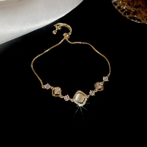 Macro detail of gold-plated bracelet featuring a cat's eye stone and adjustable pull clasp