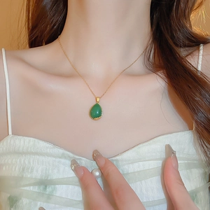 Close-up of elegant gold plated water drop green stone pendant necklace on a model