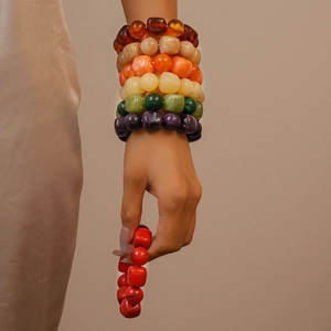 Close-up of stacked colorful acrylic resin beaded bracelets on model's wrist
