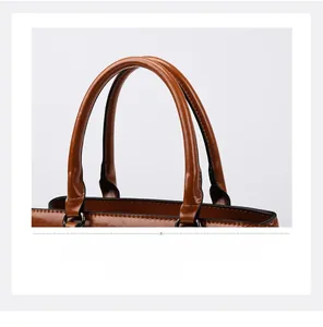 Detail of brown leather tote handle with black edge paint and dark metal hardware