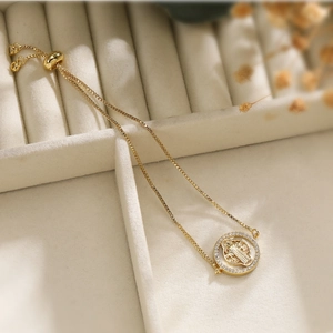 18K gold plated Saint Benedict medal bracelet with zircons on a warm white background