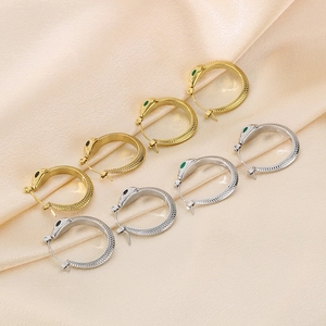 Close-up of snake-shaped titanium steel hoop earrings with scale textures on silk