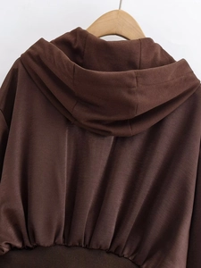 Detail of a brown hooded sweatshirt back showing ribbed hem and soft cotton fabric texture