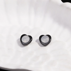 Detailed view of black heart-shaped studs on a white textured ceramic dish surface