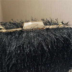 Detail of elegant black tassel evening bag featuring a premium gold metallic clasp closure