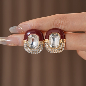 Detail of vintage oval earrings with red enamel, crystal center, and gold base