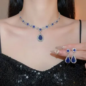 Luxury silver jewelry set with teardrop blue sapphire pendants on elegant model