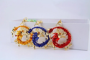 Three Chinese zodiac dragon keychains in gold, blue, and red with enamel and pearl details