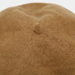 Macro detail of the top stem on a brown wool beret featuring fine fiber textures