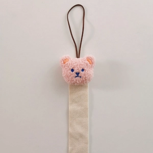 Pink plush bear hair clip organizer with a beige woven strap and brown hanging loop
