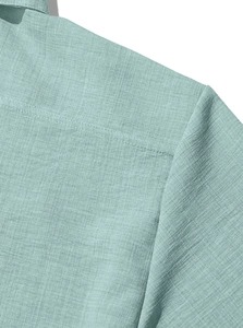 Macro detail of breathable light green fabric texture and shoulder stitching on casual shirt