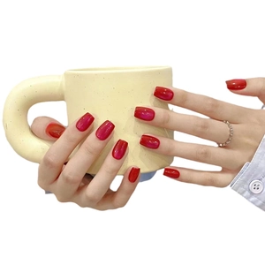 Deep red cat-eye press-on nails in short square shape shown holding a beige ceramic mug