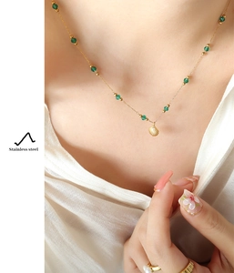 Close-up of gold stainless steel necklace with green beads and a shell pendant