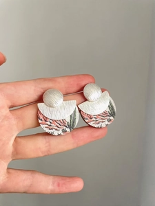 Détail de boucles d'oreilles bohèmes avec motif paysage du désert et couches en métal