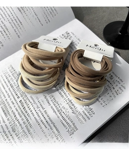 Close-up of elastic seamless hair ties set in earth tones on a vintage book page