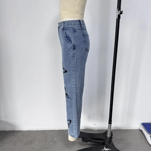 Detail view of printed butterfly pattern on the side of slim blue denim jeans