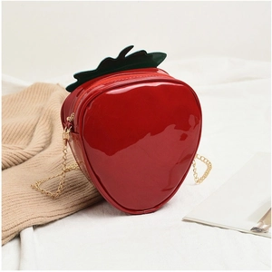 Close-up of strawberry-shaped red patent leather crossbody bag with green leaf detail