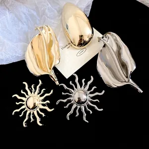 Polished gold and silver sun and leaf brooches set against a black background