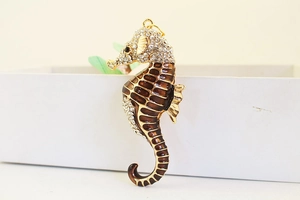 Detail of seahorse keychain with brown enamel and white rhinestones on golden alloy