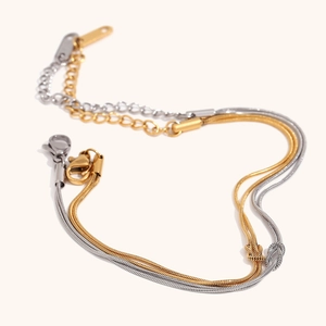 Dubbellaagse gouden en zilveren slangenarmband met knoopdetail en verstelbare karabijnsluiting