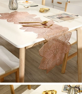 Detail of rose gold hollow floral PVC table runner on white wooden dining table with cutlery