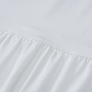Close-up of white dress fabric detailing the ruched design and fine vertical textures